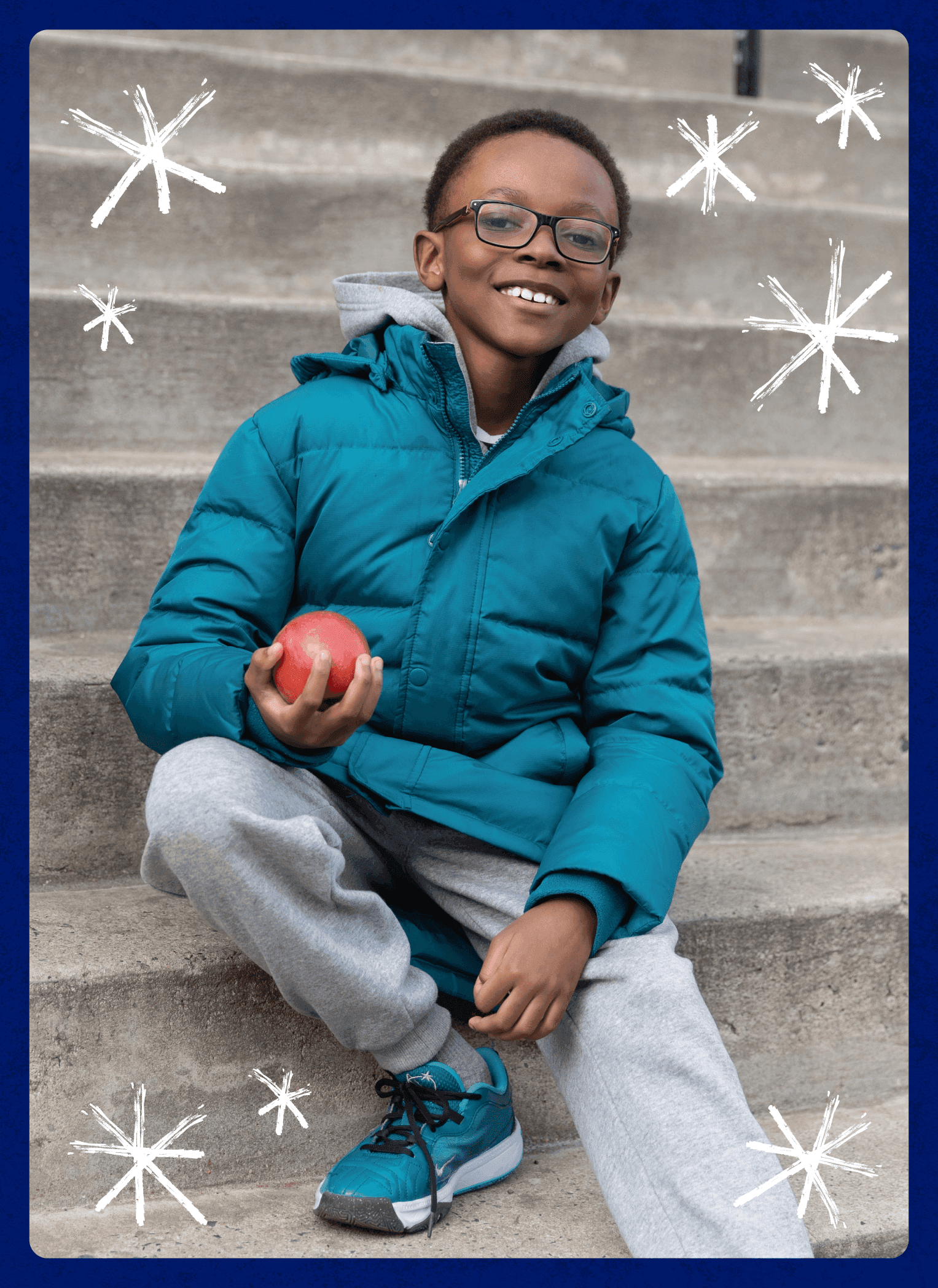 Smiling child in a teal jacket and gray sweats sits on steps holding a red apple.
