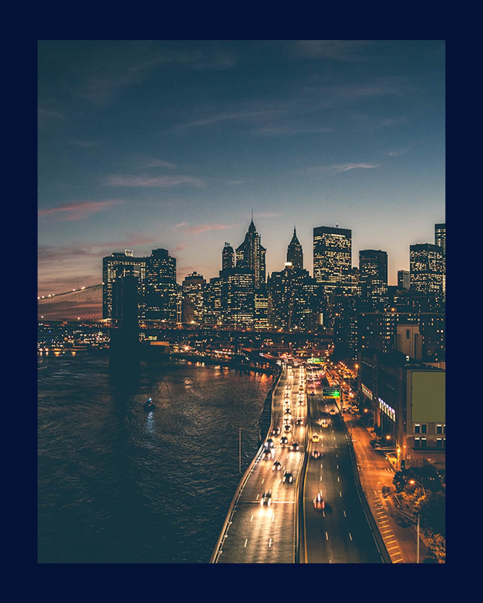 A woman in a Food Bank apron speaks to a classroom of children with raised hands, standing in front of a whiteboard and a presentation screen.