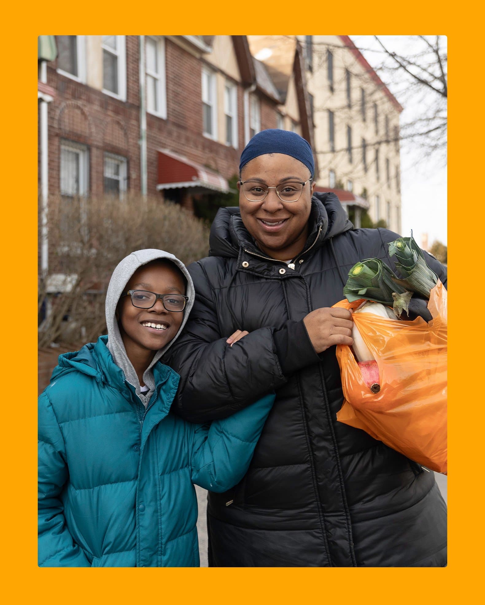 A woman and a child hold bags of food, smiling as they prepare to share a meal together.